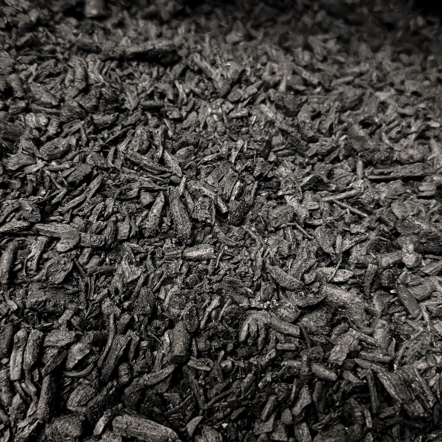 Close-up macro photo of activated biochar pieces showing the texture and size of the soil additive.