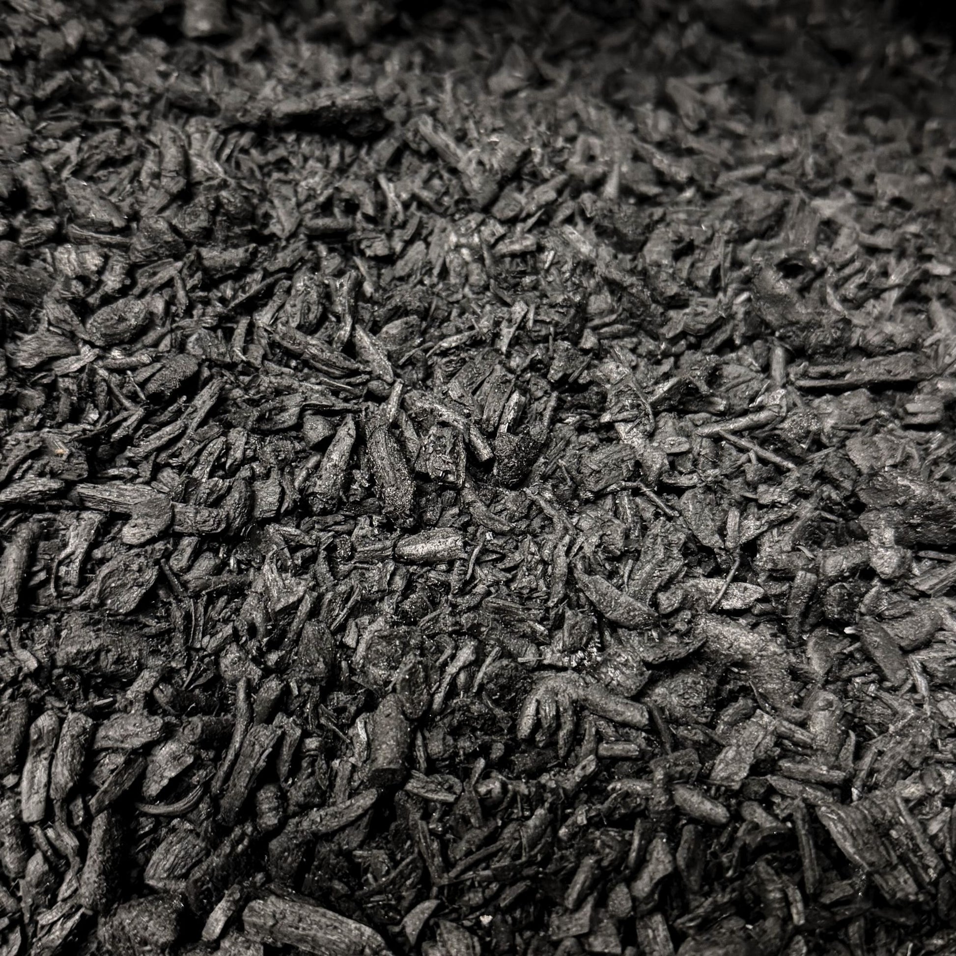 Close-up macro photo of activated biochar pieces showing the texture and size of the soil additive.