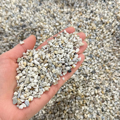 Close-up of natural 3–5mm aquarium gravel held in hand showing rounded quartz stones suitable for fish tank substrate and aqua scaping.